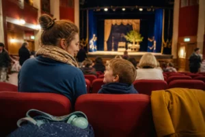 Parent et enfant observent sereinement la scène avant une sortie au théâtre en famille sans stress